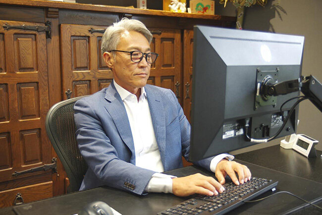 パソコンに向かって作業をする新栄重機土木の新井社長