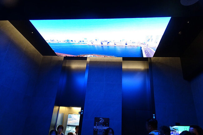 東京豊洲　万葉倶楽部の入口のエレベーターの天井には巨大なデジタルサイネージが迎える。温泉を楽しむためのトンネルのような設えだ