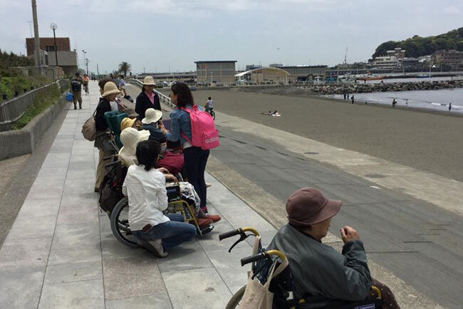 電車に乗って出かけた江ノ島の海辺でくつろぐ入居者