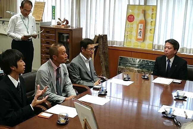 太田豊彦大分県副知事（当時・右）が「このジュースは甘味料を一切使用せず、みかんの素材だけを生かしてとても美味しい」と太鼓判を押した