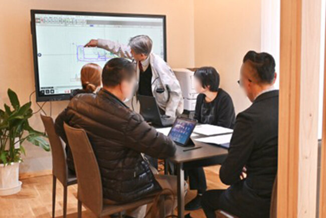 電子黒板の大画面を使った図面の解説を顧客に行っている