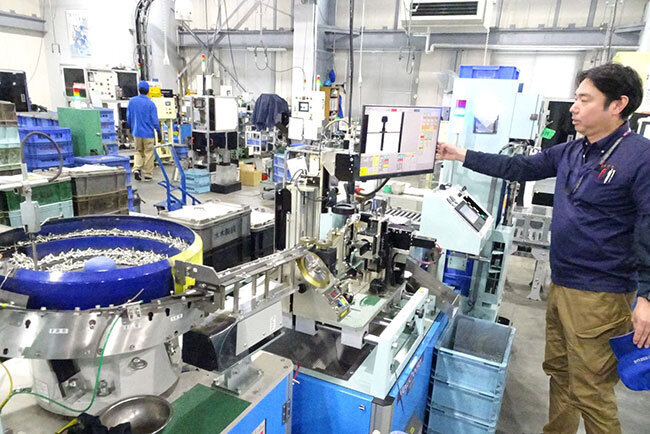 工場画像監視システムを前に「ラインに流れるネジの精度を1本ずつセンサーでチェックして、不良があればアラームが知らせてくれて画像で確認する」と昇（のぼる）智幸主事が説明する