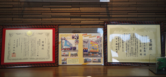 （左）警察署や自衛隊から贈られた感謝状、（右）八幡警察署と連携して行ったデザイントラックの表彰状