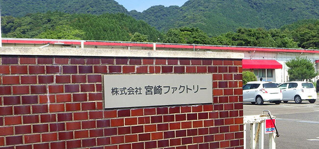 工場の門に書かれた「宮崎ファクトリー」の社名