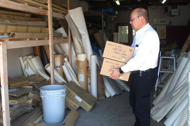 内装工事に必要なクロスなどを倉庫に片付ける後藤寛之社長