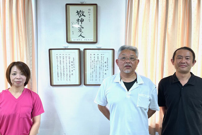 理念を基にした取り組みを語ってくれた黒澤瑞樹施設長、金子恵司課長、高橋知美主任。「敬神愛人」の前で