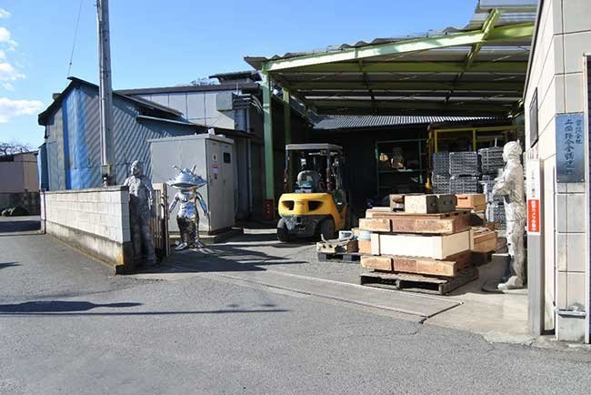 地元銀行主催の展示会に出品したオブジェが並ぶ本社社屋。奥にアルミ合金のインゴットが積まれている