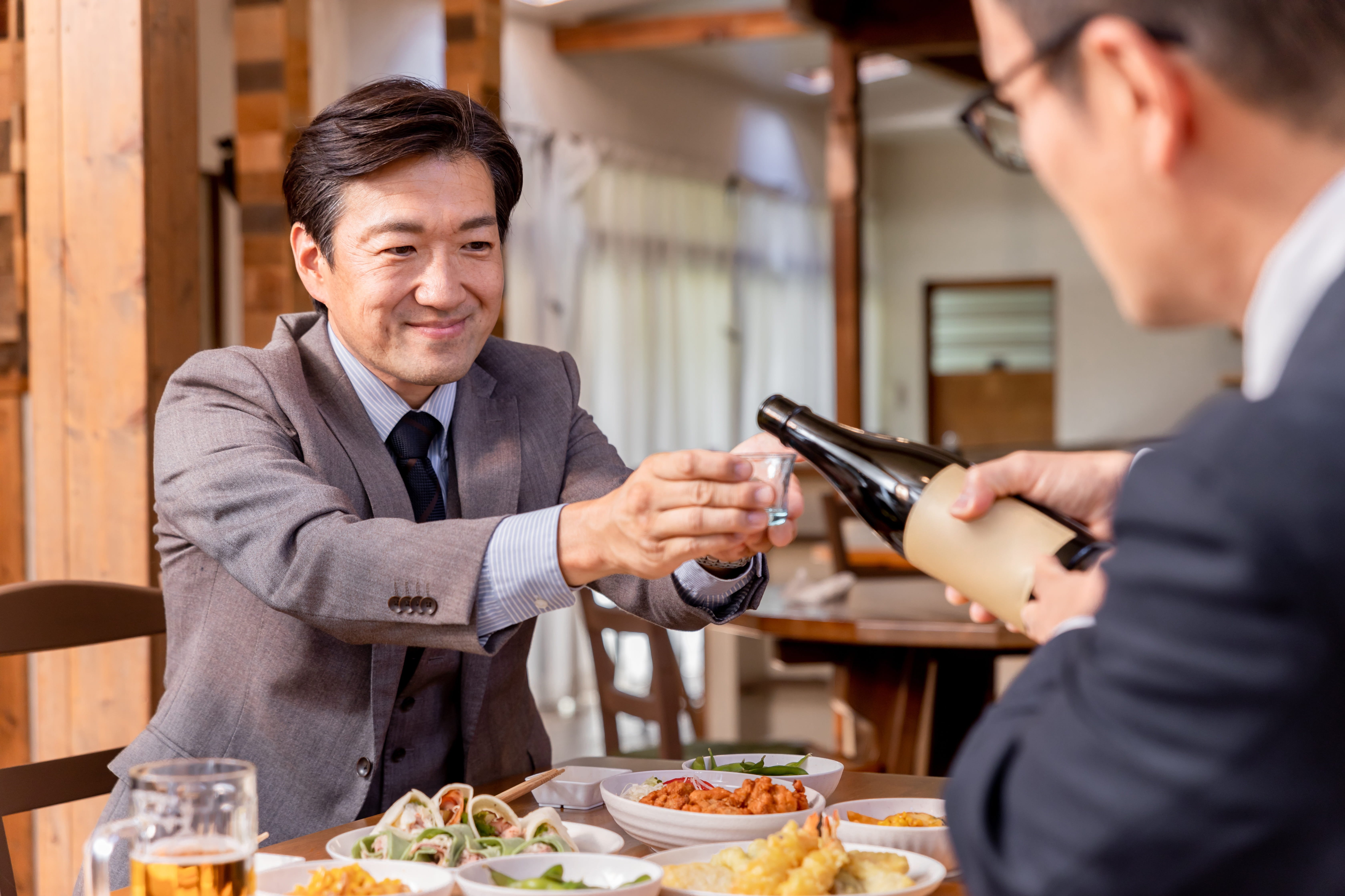 接待・会食・飲み会・親睦会でお酌される笑顔のビジネスマン  