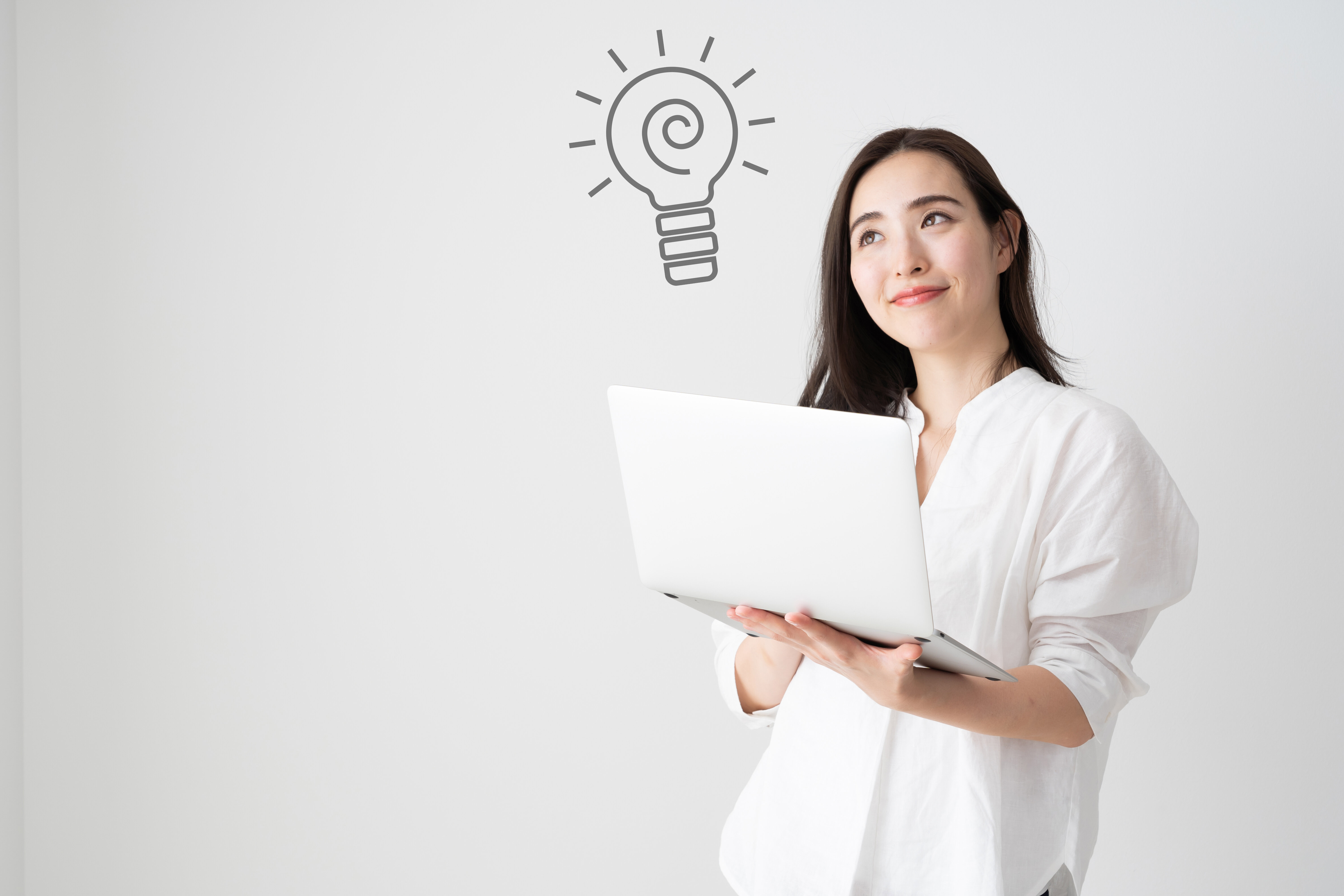 ノートパソコンを手に持ち、ひらめきを得たような表情を浮かべる女性の後ろに電球のイラスト。DX推進に向けた前向きな姿勢や新しい発想を象徴するイメージ。