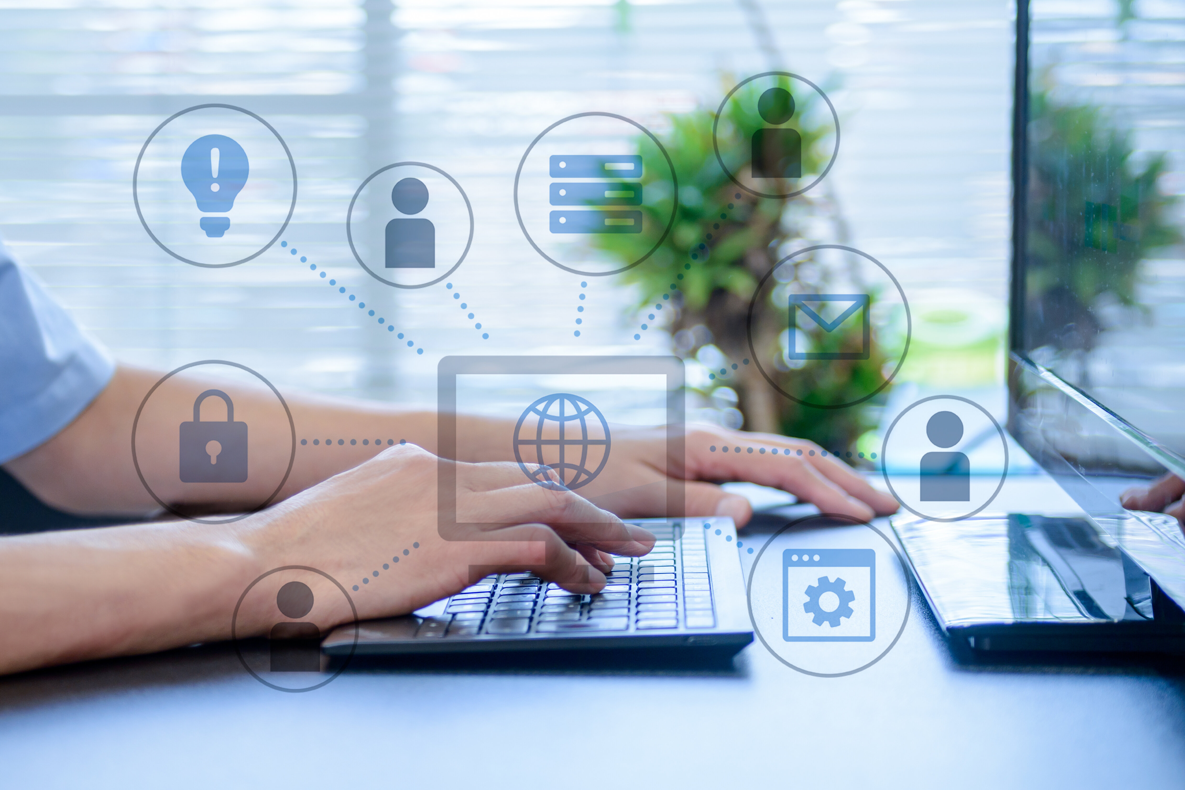 業務のデジタル化・DX推進をイメージした写真。パソコン操作中の手元に、クラウド、セキュリティ、ユーザー管理、設定、メールなど複数のIT関連アイコンが重ねて表示されている。