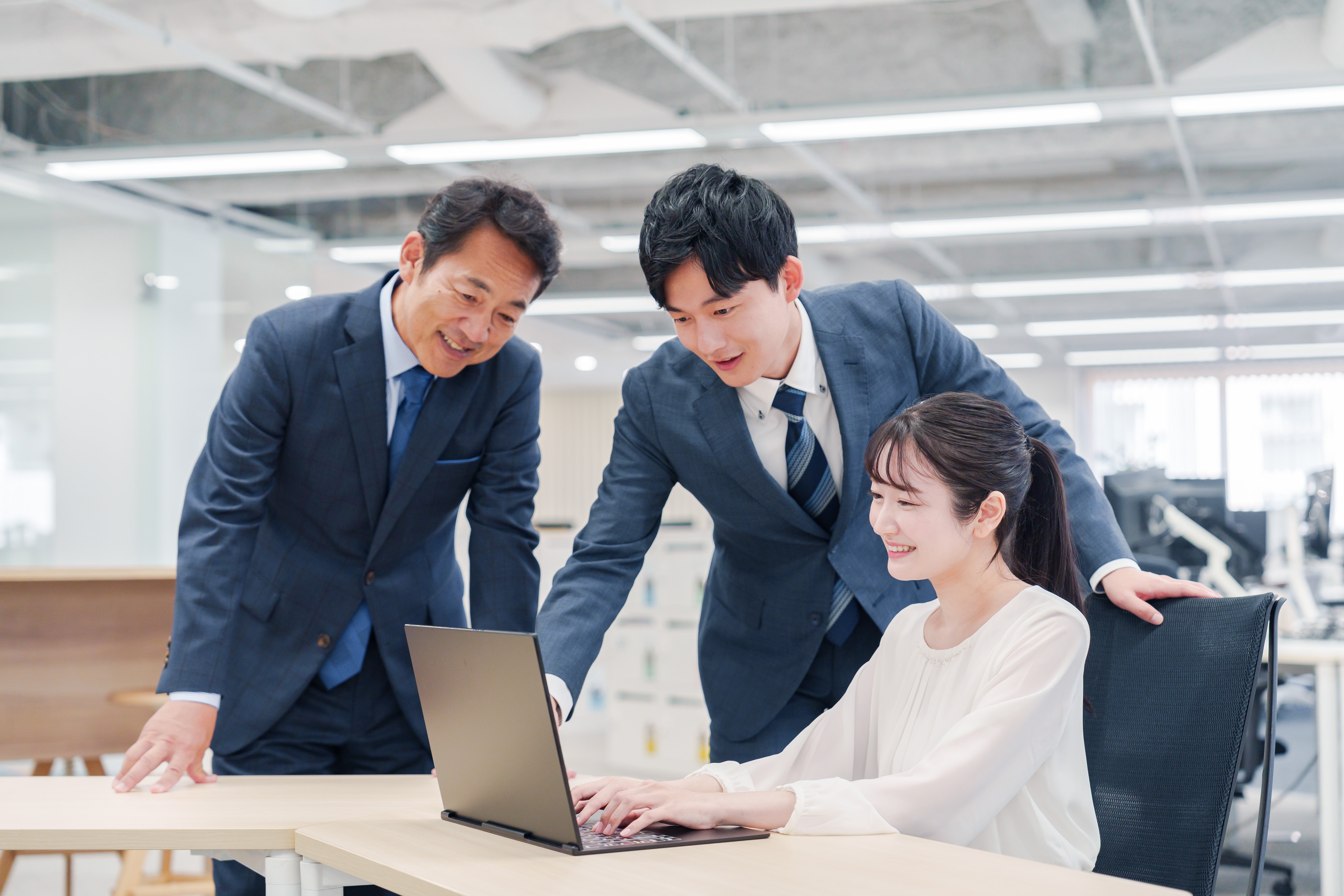 チームでPCを確認しながら生成AI導入を検討するビジネスシーン