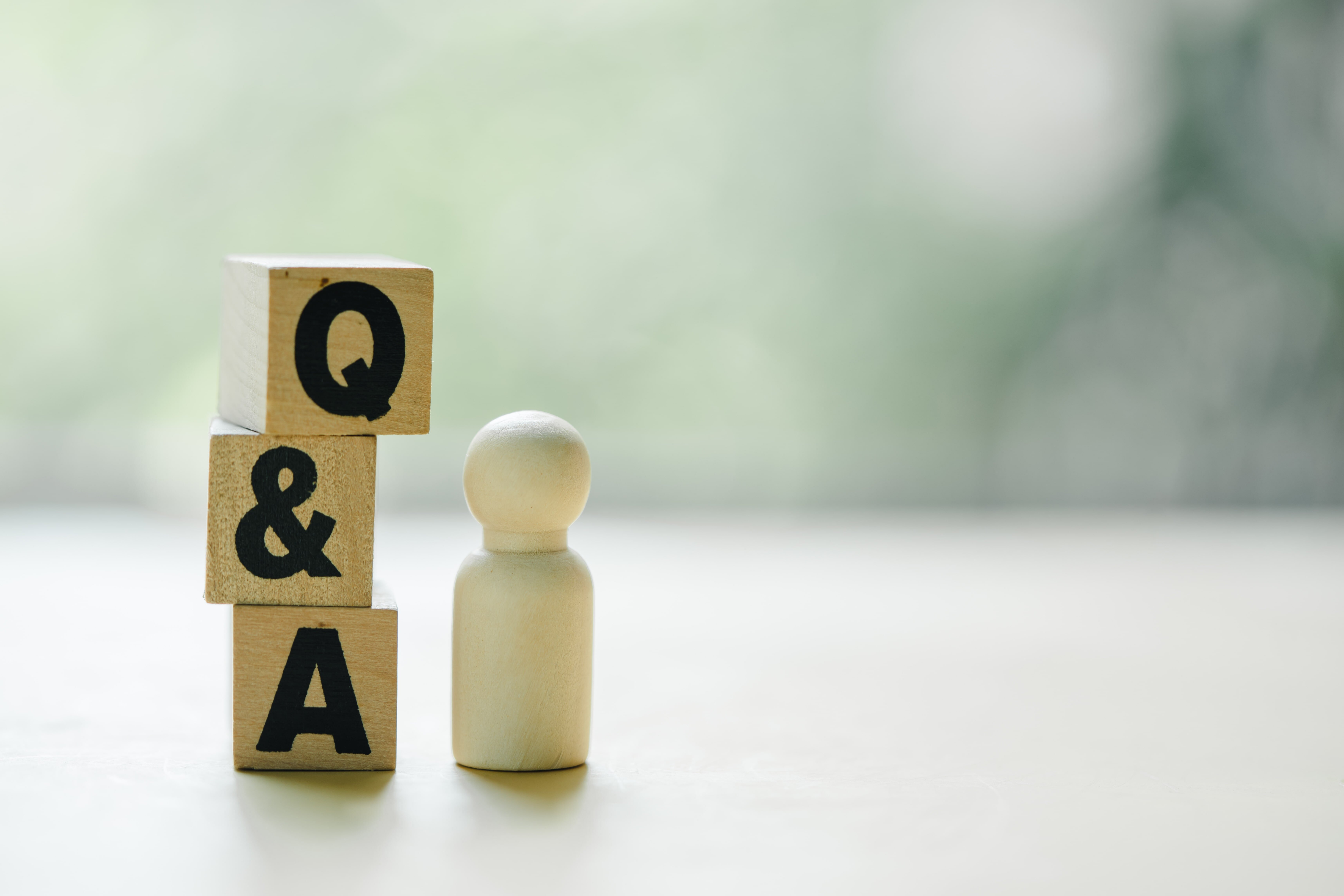 Q&Aと書かれたブロックと人形の置物を並べた写真。36協定に関するよくある質問をイメージしたもの。