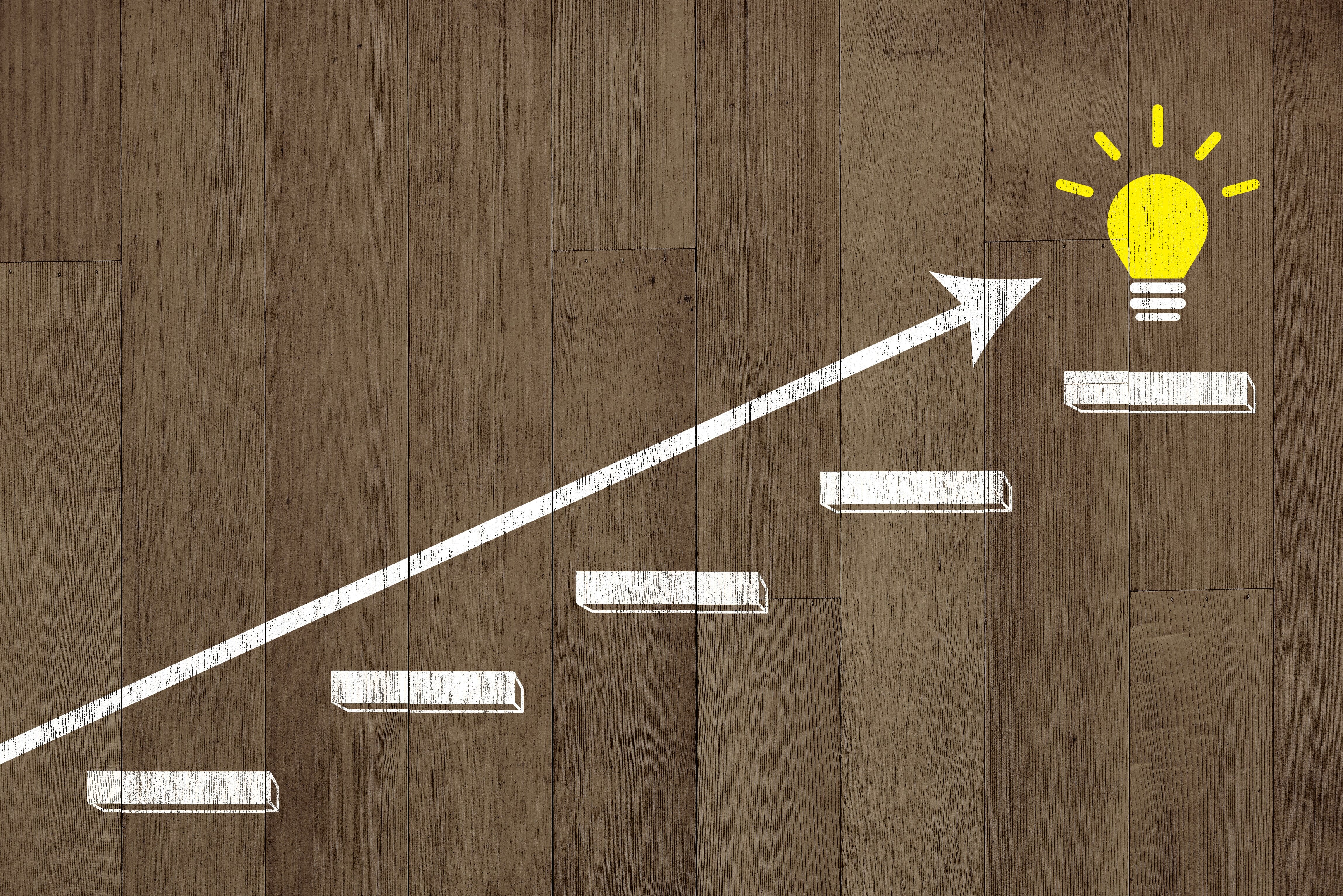 階段状に配置されたブロックと矢印、ゴール地点にある電球を描いたイラスト。BCP策定の手順やステップアップをイメージしている。