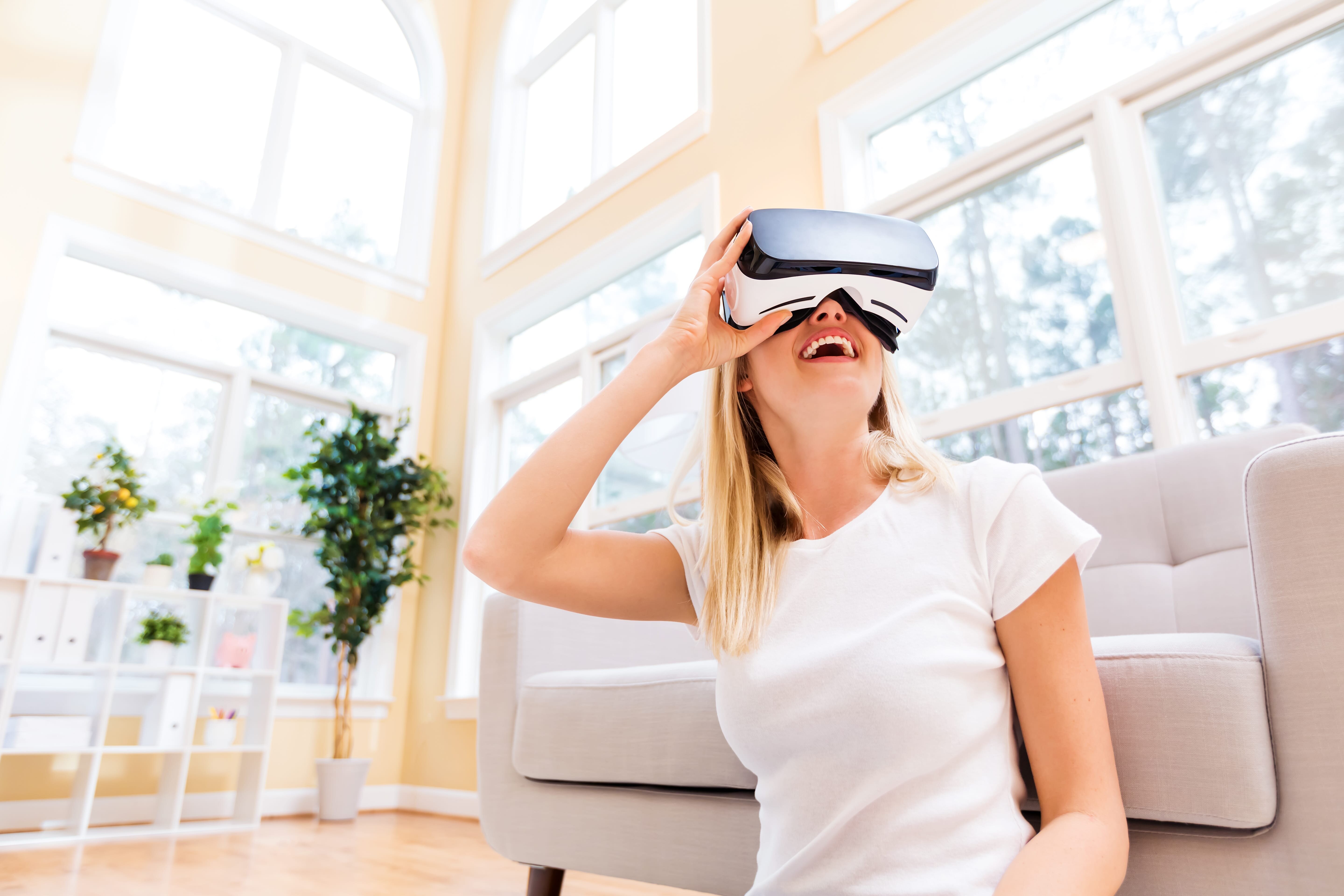 VRゴーグルを装着し、バーチャル体験を楽しむ女性。VRを活用した不動産内覧など、不動産テックサービスの一例を表している。