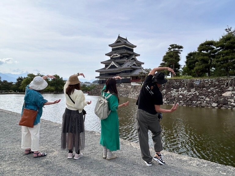 松本城とお掘りの前でCのマーク。あーくじゃさん、なんのポーズですか？