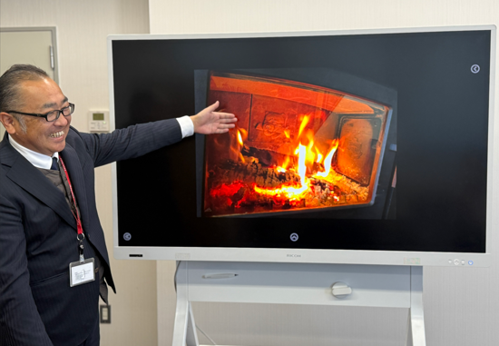 自慢の薪ストーブを熱く語る かつあきさん(アイアンドッグのマークが奥にちらり)