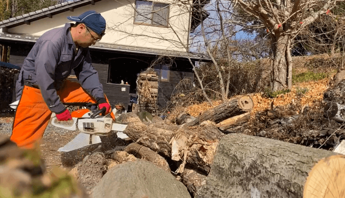 チェーンソーで木材から薪に切断している超集中のかつあきさん